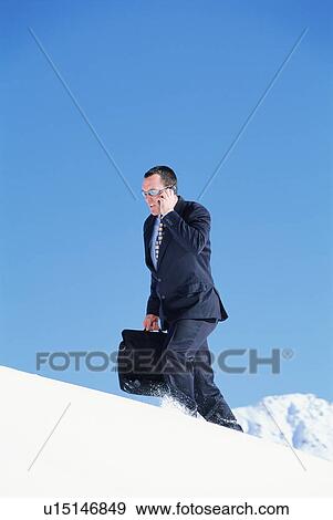 Businessman outdoors on snowy mountain using cellular phone View Large Photo Image Stock Photo - Businessman outdoors on snowy mountain using cellular phone. Fotosearch