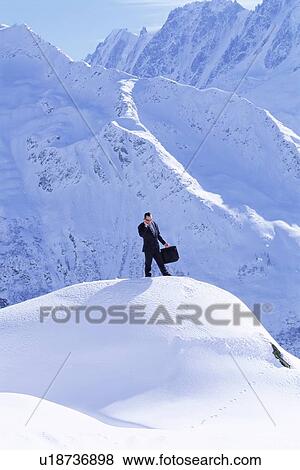 Stock Photo - Businessman outdoors on snowy mountain using cellular phone. Fotosearch