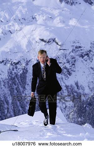 Businessman outdoors on snowy mountain using cellular phone View Large Photo Image Stock Photograph - Businessman outdoors on snowy mountain using cellular phone. Fotosearch