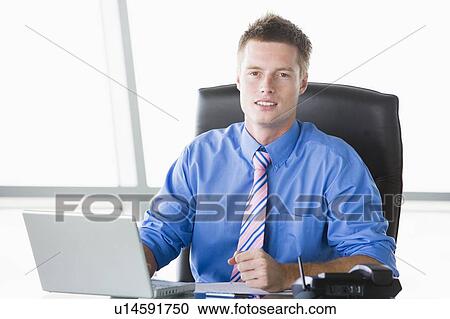 Businessman sitting in office with laptop View Large Photo Image Stock Image - Businessman sitting in office with laptop. Fotosearch