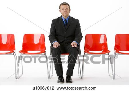 Stock Image - Businessman Sitting In Row Of Empty Chairs . Fotosearch