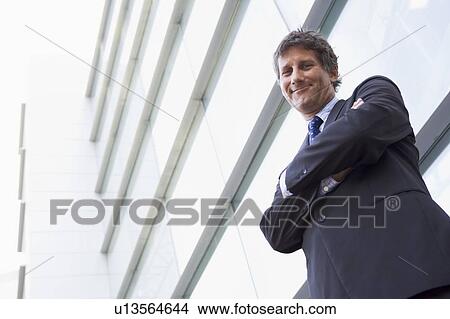 Businessman standing outdoors by building smiling View Large Photo Image Picture - Businessman standing outdoors by building smiling. Fotosearch