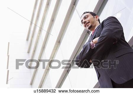 Businessman standing outdoors by building smiling (high key/selective focus) View Large Photo Image Stock Image - Businessman standing outdoors by building smiling (high key/selective focus). Fotosearch