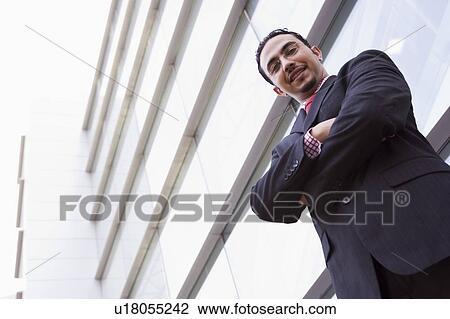 Businessman standing outdoors by building smiling (high key/selective focus) View Large Photo Image Stock Image - Businessman standing outdoors by building smiling (high key/selective focus). Fotosearch