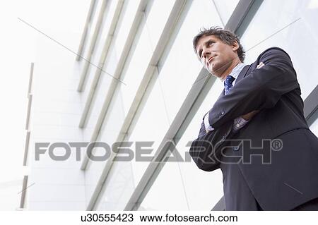 Stock Image - Businessman standing outdoors by building. Fotosearch