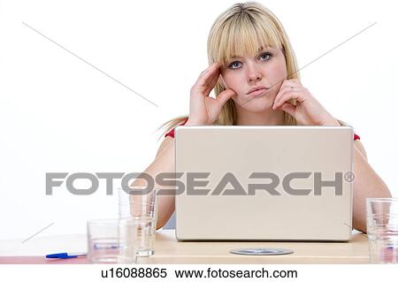 Stock Photography - Businesswoman sitting in boardroom with laptop looking unhappy. Fotosearch