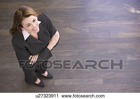 Stock Image - Businesswoman standing indoors smiling. Fotosearch