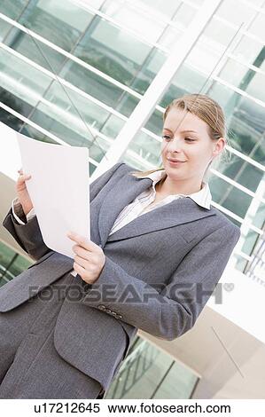 Stock Photography - Businesswoman standing outdoors reading paperwork. Fotosearch