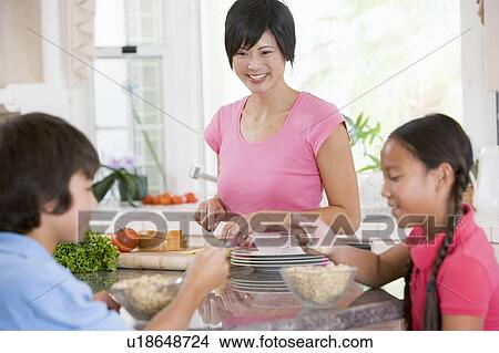 Children Enjoying Breakfast While Mother Is Preparing Food View Large Photo Image Picture - Children Enjoying Breakfast While Mother Is Preparing Food. Fotosearch