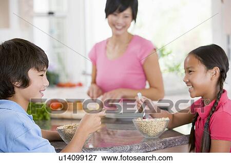 Children Enjoying Breakfast While Mother Is Preparing Food View Large Photo Image Stock Photo - Children Enjoying Breakfast While Mother Is Preparing Food. Fotosearch