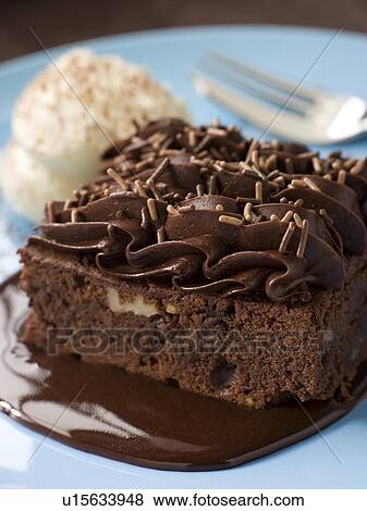 Stock Photo - Chocolate Fudge Brownie With Chocolate Fudge Sauce And Cream. Fotosearch