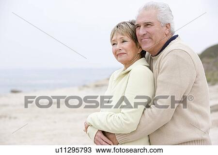 Stock Image - Couple at the beach embracing and smiling. Fotosearch