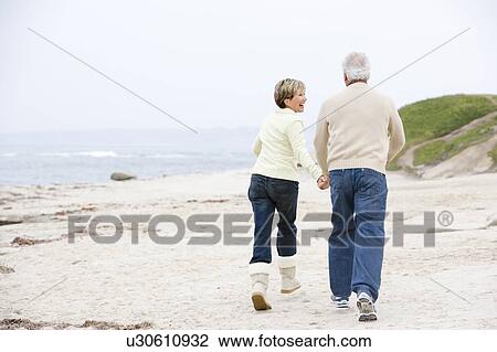 Couple at the beach holding hands and smiling View Large Photo Image Stock Image - Couple at the beach holding hands and smiling. Fotosearch