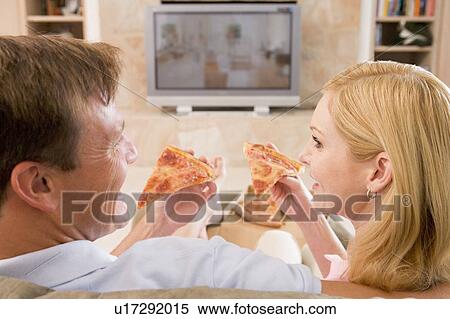 Stock Photography - Couple Enjoying Pizza In Front Of TV. Fotosearch