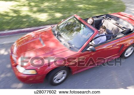 Stock Image - Couple in convertible car smiling. Fotosearch