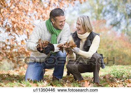 Couple outdoors holding leaves and smiling (selective focus) View Large Photo Image Stock Photograph - Couple outdoors holding leaves and smiling (selective focus). Fotosearch