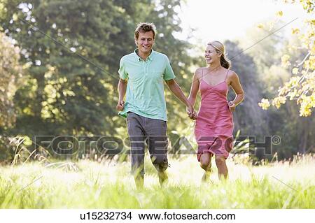 Couple running outdoors holding hands and smiling View Large Photo Image Picture - Couple running outdoors holding hands and smiling. Fotosearch