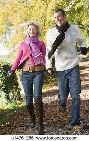 Couple running outdoors on path in park smiling (selective focus) View Large Photo Image Stock Photograph - Couple running outdoors on path in park smiling (selective focus). Fotosearch