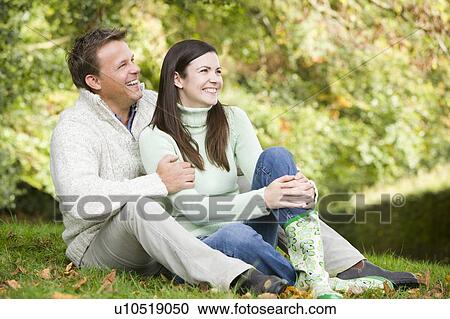 Couple sitting outdoors smiling (selective focus) View Large Photo Image Stock Image - Couple sitting outdoors smiling (selective focus). Fotosearch