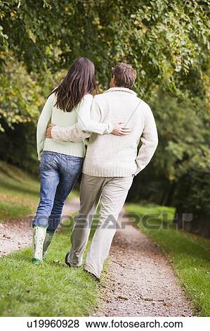 Couple walking outdoors on path in park (selective focus) View Large Photo Image Stock Photo - Couple walking outdoors on path in park (selective focus). Fotosearch