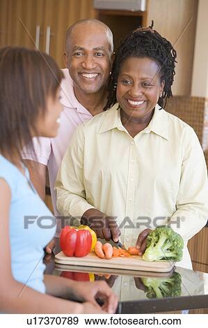 Stock Photo - Couple With Daughter Preparing meal, mealtime. Fotosearch