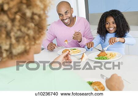 Stock Image - Family Eating A meal, mealtime Together . Fotosearch