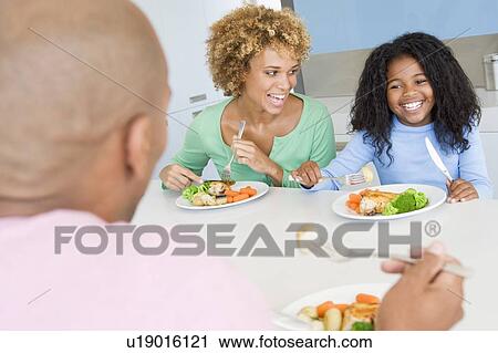 Stock Image - Family Eating A meal, mealtime Together . Fotosearch