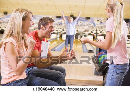 Stock Image - Family in bowling alley cheering and smiling. Fotosearch