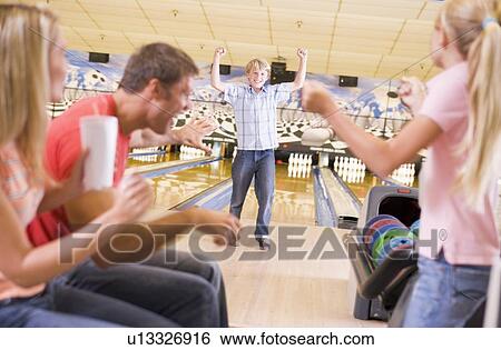 Stock Photograph - Family in bowling alley cheering and smiling. Fotosearch