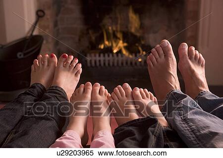 Stock Photography - Family of feet warming at a fireplace. Fotosearch