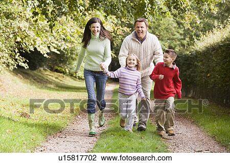 Family outdoors walking on path holding hands and smiling (selective focus) View Large Photo Image Stock Image - Family outdoors walking on path holding hands and smiling (selective focus). Fotosearch