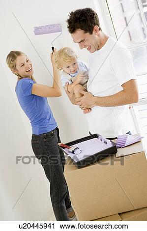 Stock Image - Family painting room in new home smiling. Fotosearch