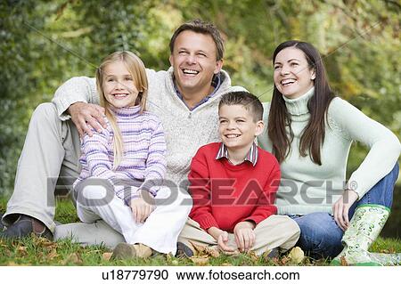 Family sitting outdoors in park smiling (selective focus) View Large Photo Image Stock Image - Family sitting outdoors in park smiling (selective focus). Fotosearch