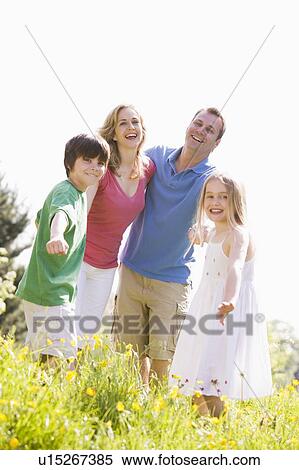 Stock Photography - Family standing outdoors holding hands smiling. Fotosearch