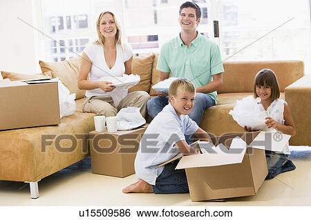 Stock Photograph - Family unpacking boxes in new home smiling. Fotosearch