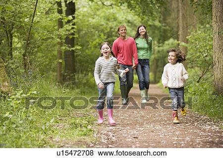 Stock Photo - Family walking on path holding hands smiling. Fotosearch