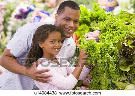 Stock Photo - Father and daughter shopping for lettuce at a grocery store. Fotosearch