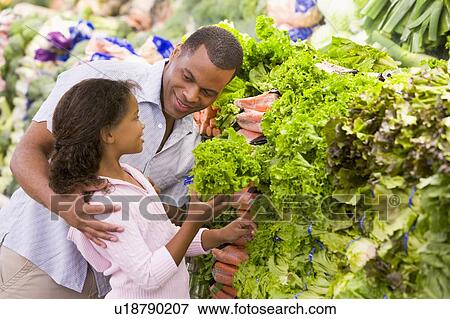 Stock Photo - Father and daughter shopping for lettuce at a grocery store. Fotosearch