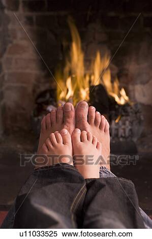 Stock Photography - Father and son's feet warming at a fireplace. Fotosearch