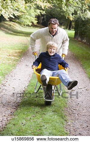 Stock Photograph - Father pushing son in wheelbarrow. Fotosearch