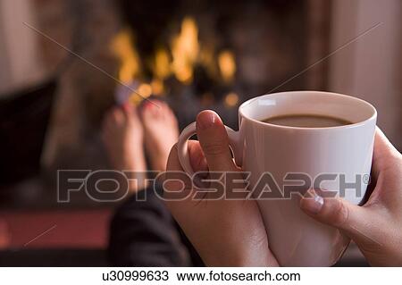 Feet warming at a fireplace with hands holding coffee View Large Photo Image Stock Image - Feet warming at a fireplace with hands holding coffee. Fotosearch