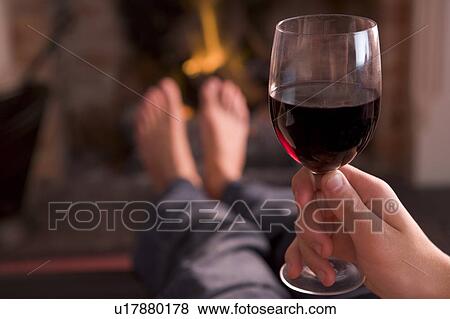 Feet warming at fireplace with hand holding wine View Large Photo Image Stock Photo - Feet warming at fireplace with hand holding wine. Fotosearch