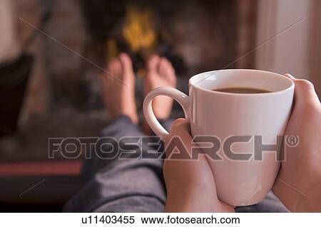 Feet warming at fireplace with hands holding coffee View Large Photo Image Stock Photography - Feet warming at fireplace with hands holding coffee. Fotosearch