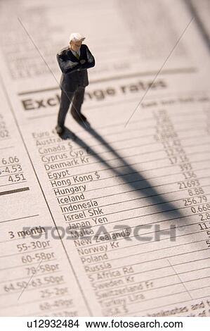 Picture - Figurine Of A Businessman With Arms Crossed Standing On A Financial Newspaper. Fotosearch