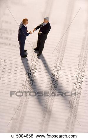 Figurines Of Two Businessmen Shaking Hands On A Financial Newspaper View Large Photo Image Stock Photo - Figurines Of Two Businessmen Shaking Hands On A Financial Newspaper. Fotosearch
