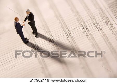 Stock Photo - Figurines Of Two Businessmen Shaking Hands On A Financial Newspaper. Fotosearch