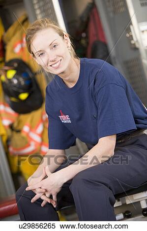 Firewoman sitting on bench in fire station locker room View Large Photo Image Stock Photography - Firewoman sitting on bench in fire station locker room. Fotosearch