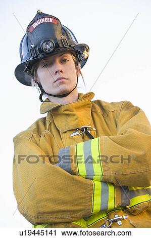 Stock Image - Firewoman standing outdoors wearing helmet. Fotosearch