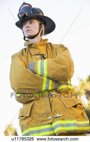 Stock Photograph - Firewoman standing outdoors wearing helmet. Fotosearch