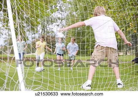 Stock Image - Five young friends playing soccer. Fotosearch